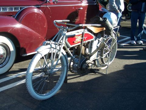 1990 Ford Bronco - A vintage motorcycle with a red gas tank and white tires is parked next to a classic car.