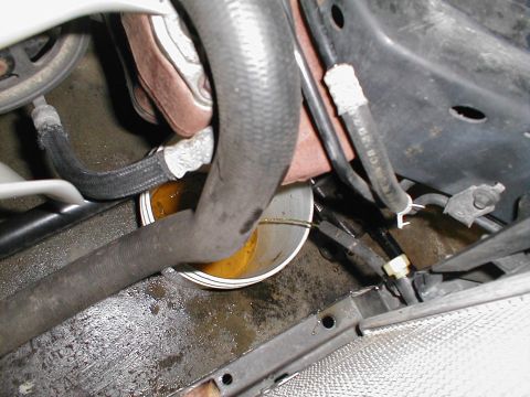 1997 Ford Crown Victoria - A close-up view of automotive hoses and a bowl collecting a fluid leak under the hood.