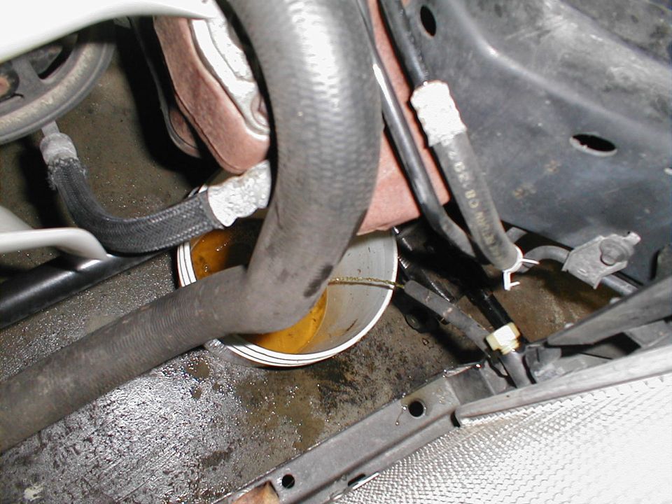 Engine bay with hoses and a bowl catching a coolant leak