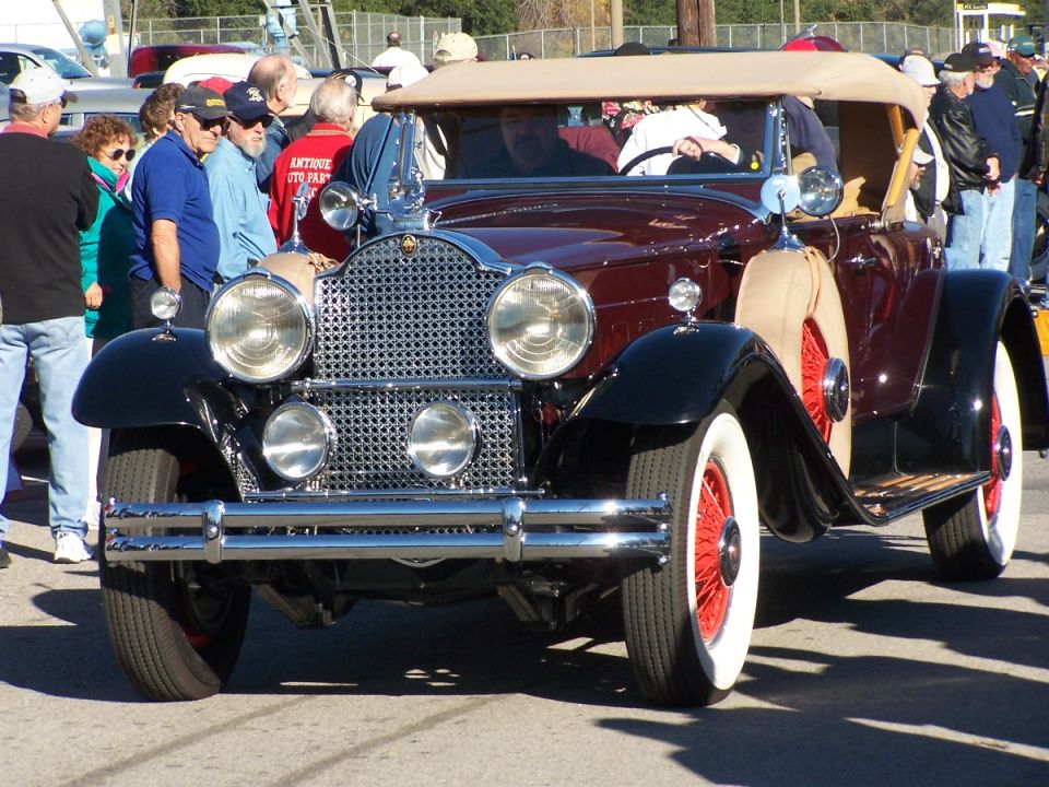 Maroon convertible with tan top, red wire wheels, and whitewall tires