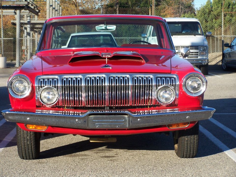 Red classic car front view, chrome grille, dual headlights, hood scoop, parked outdoors