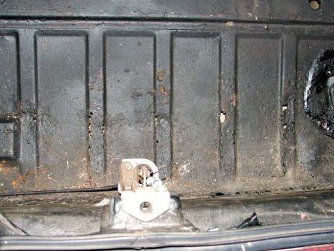 1974 Porsche 914 - The underside of a car shows signs of rust and wear, with a visible latch mechanism.