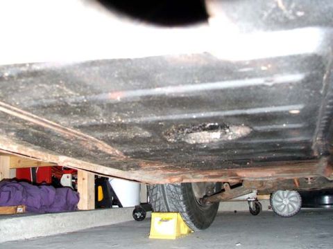 1974 Porsche 914 - The underside of a vehicle is visible, with a tire and some stored items in the background.