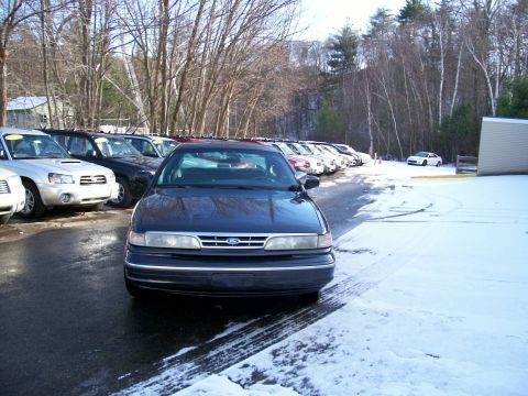 2001 Ford Crown Victoria - A dark blue 2001 Ford Crown Victoria is parked in a lot with snow on the ground and other vehicles in the background.