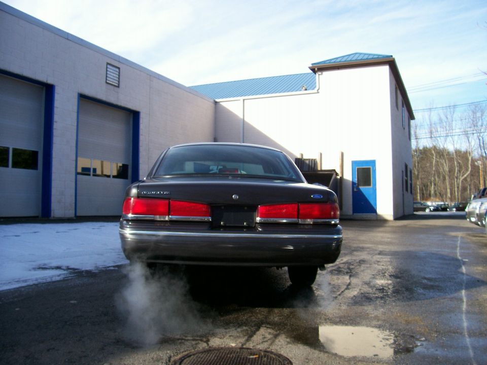 Dark sedan with exhaust smoke, rear view