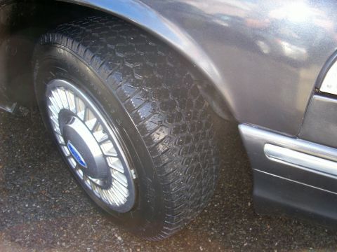 2001 Ford Crown Victoria - A close-up view of a car's wheel and tire, showing the tread pattern and fender detail.