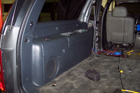 2002 Chevrolet Suburban - Vehicle interior with speaker enclosure and exposed wiring, possibly undergoing modifications.
