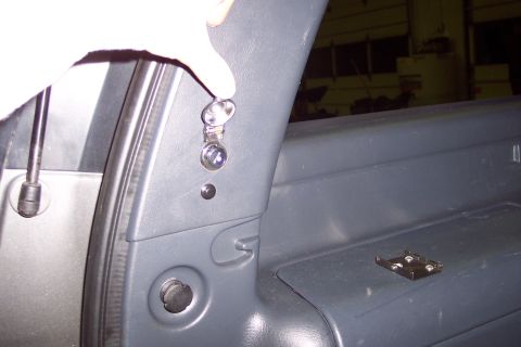 2002 Chevrolet Suburban - A hand operates a chrome latch on a gray interior trim panel.