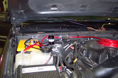 2002 Chevrolet Suburban - Aftermarket wiring and a yellow battery are visible in the engine bay of a vehicle.