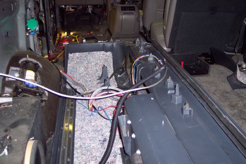 2002 Chevrolet Suburban - The interior of a vehicle is shown with the floor panels removed, revealing extensive wiring and insulation.