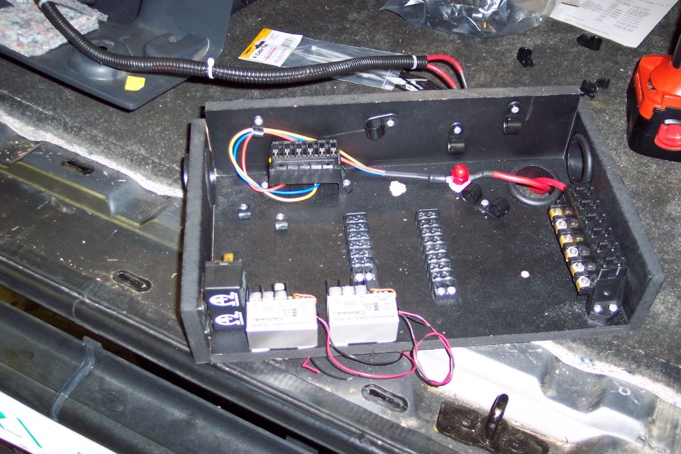 Electrical wiring box with relays, terminal blocks, and red and blue wires installed in a vehicle's interior