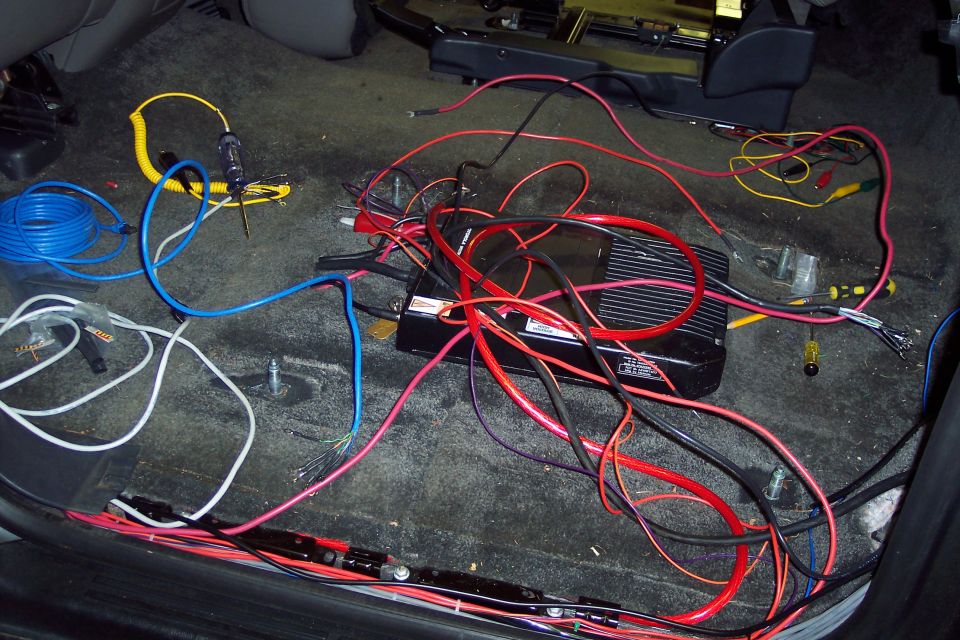Car interior with amplifier and lots of tangled wires on the floor