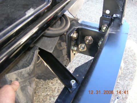 1996 Ford Bronco - Close-up of a black bumper mounting bracket, showing bolts and attachment points, with a tire visible in the background.