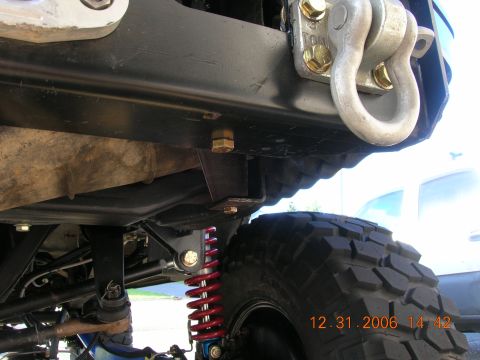 1996 Ford Bronco - Close-up view of a vehicle's undercarriage, showing suspension components and a tow hook.