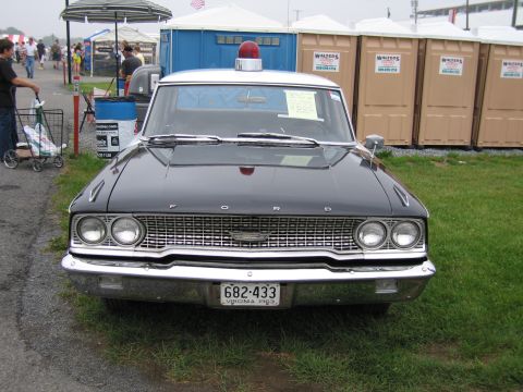 1991 Ford LTD Crown Victoria - Front view of a black vintage Ford sedan with FORD hood lettering and a red roof beacon, displayed on grass with a Virginia 1963 license pl…