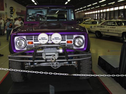 1991 Ford LTD Crown Victoria - Front view of a purple lifted early Ford Bronco with a winch, push bar and Super Off-Roader lamps, displayed indoors behind a chain barrier.