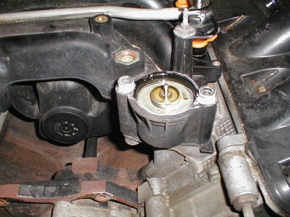 Engine intake manifold and thermostat housing with visible text 'SUPERMOTORS'