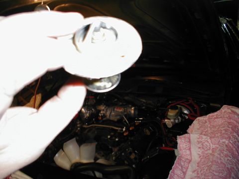 1997 Ford Crown Victoria - Close-up of a hand holding a part over the engine of a 1997 Ford Crown Victoria during an intake swap.
