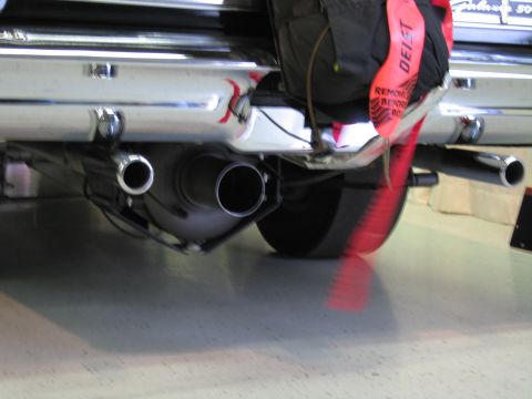 1991 Ford LTD Crown Victoria - Close-up of polished dual exhaust tips beneath a car's chrome bumper, with a red DEIST parachute strap hanging down.