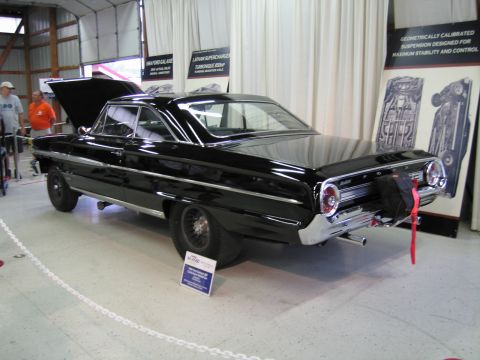 1991 Ford LTD Crown Victoria - black Ford full-size two-door with raised hood and a drag parachute pack is displayed beside posters of engine and suspension specs.