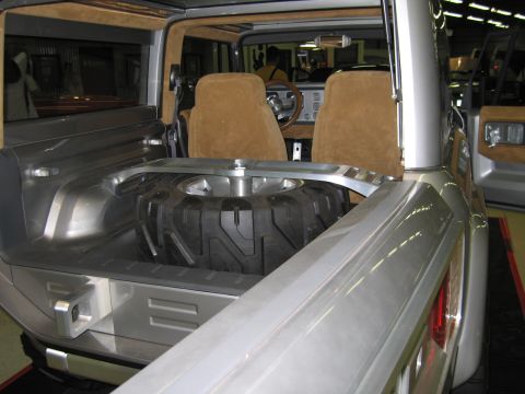 1991 Ford LTD Crown Victoria - chunky off-road spare tire is mounted in the open rear bed of a silver concept truck-SUV, with tan suede seats visible ahead.