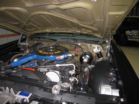 1991 Ford LTD Crown Victoria - Open engine compartment of a tan-hooded classic car featuring a blue air cleaner, black brake booster and detailed wiring.