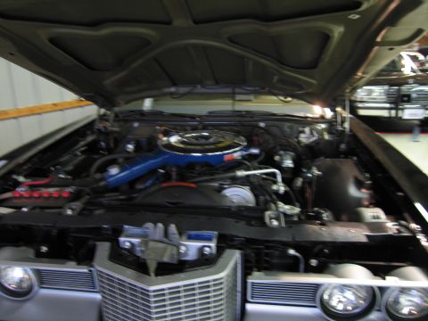 1991 Ford LTD Crown Victoria - Out-of-focus view of a classic car engine bay with a blue air cleaner above a polished chrome front grille and headlights.