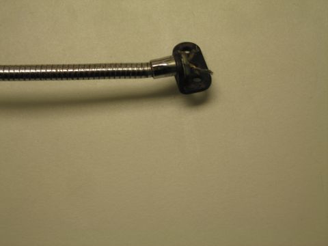 1991 Ford LTD Crown Victoria - Close-up of the chrome flexible neck and black plastic socket fitting of a gooseneck lamp on a tan surface.