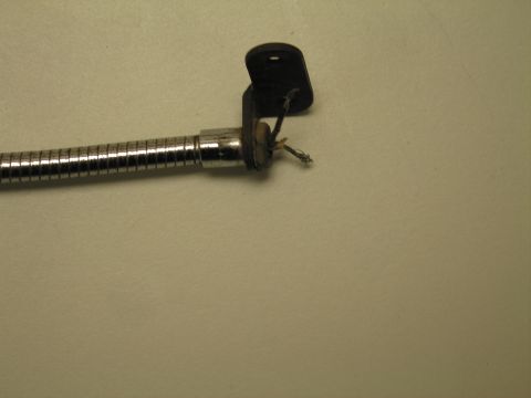 1991 Ford LTD Crown Victoria - Detail of a chrome flexible gooseneck neck terminating in a black bracket with a frayed wire end on a tan surface.
