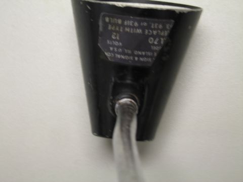 1991 Ford LTD Crown Victoria - Close-up of a black conical lamp shade bearing a partial sign and signal company label noting 12 volts and bulb type.