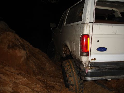 1989 Ford Bronco - Muddy 1989 Ford Bronco navigating a dirt hill in the dark.