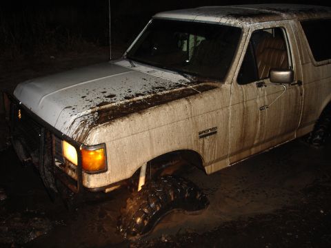 1989 Ford Bronco - White 1989 Ford Bronco stuck deep in mud at night.