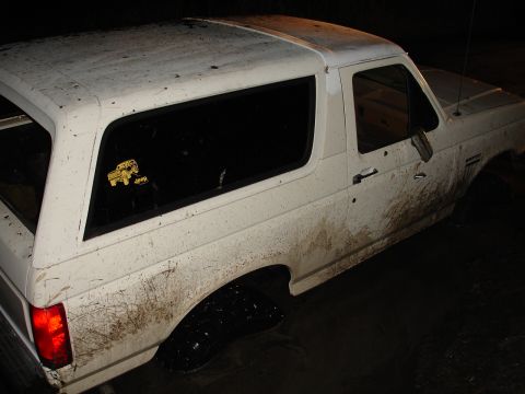 1989 Ford Bronco - This muddy white SUV is seen from a 3/4 front angle, with a Jeep sticker visible on the rear passenger window.