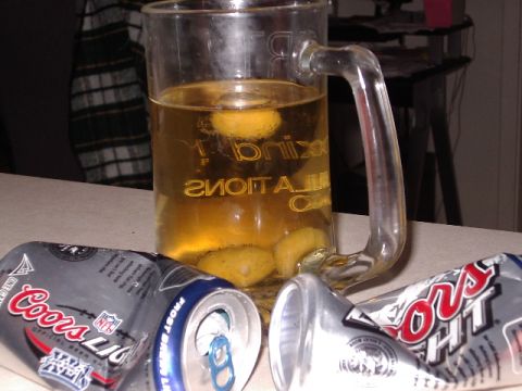 1985 Ford Bronco - A beer mug filled with liquid and lemons sits next to two crushed Coors Light cans on a table.