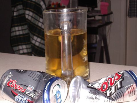 1985 Ford Bronco - A mug of beer sits beside two empty, crushed beer cans on a table.