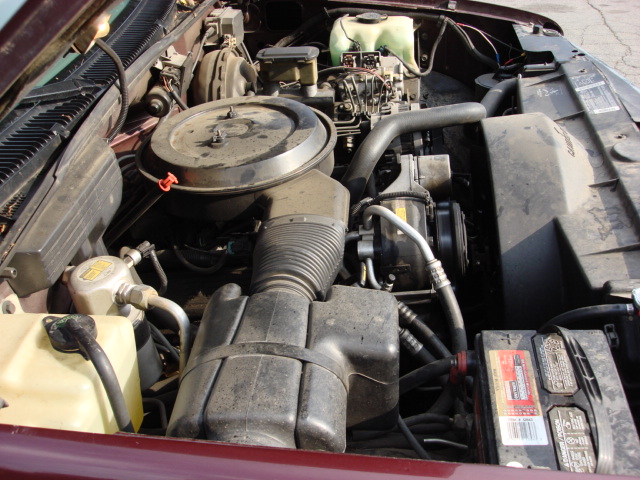 Engine bay of a maroon vehicle showing air cleaner and battery