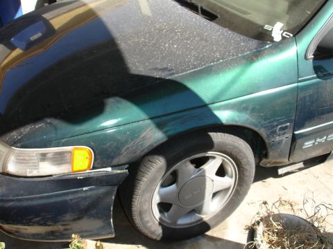 1995 Ford Taurus - Front view of a green 1995 Ford Taurus, showing the fender and wheel.