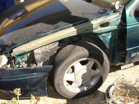 1995 Ford Taurus - Front fender and wheel of a 1995 Ford Taurus showing damage.