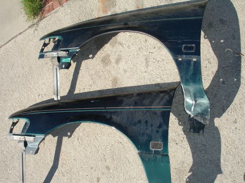 1995 Ford Taurus - Two detached car fenders are shown laid out on a concrete surface.