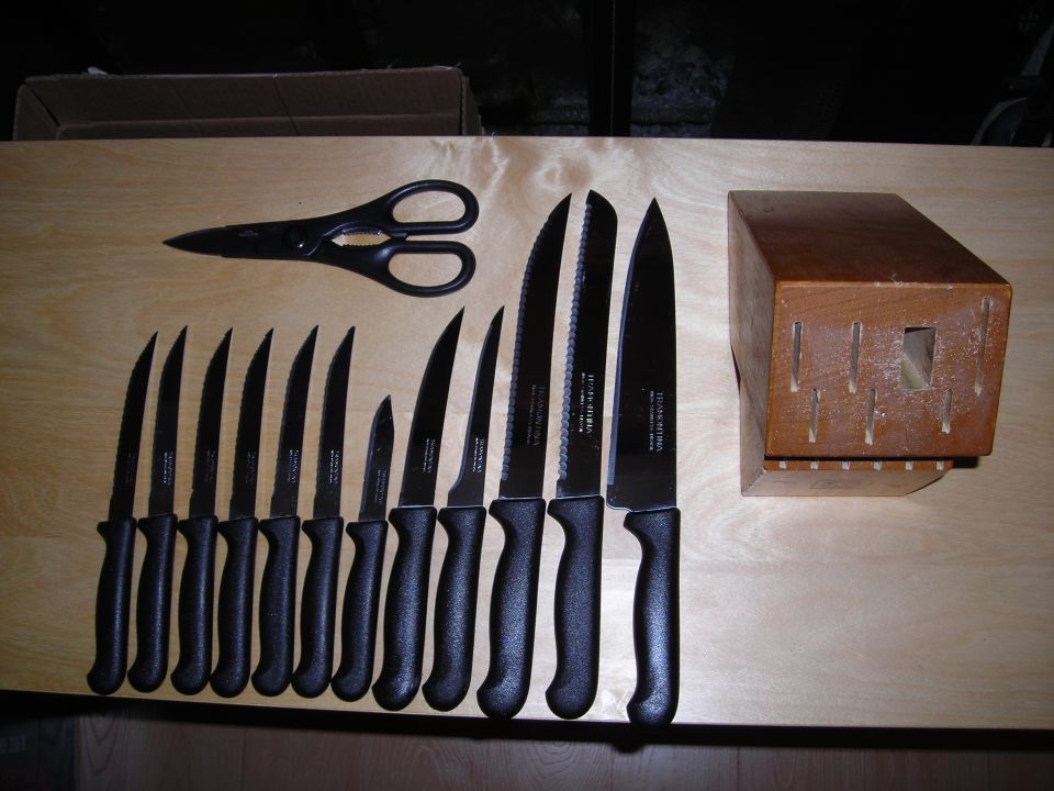 Set of kitchen knives, kitchen shears, and a wooden knife block on a wooden surface