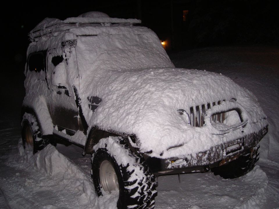 Snow-covered 2003 Jeep TJ with a roof rack, parked in snow