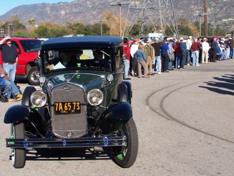 1990 Ford Bronco - Front view of a 1931 Ford Model A coupe with a crowd and a red SUV behind it.