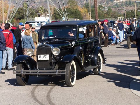 1990 Ford Bronco - A classic black sedan is parked on a street with people gathered around.