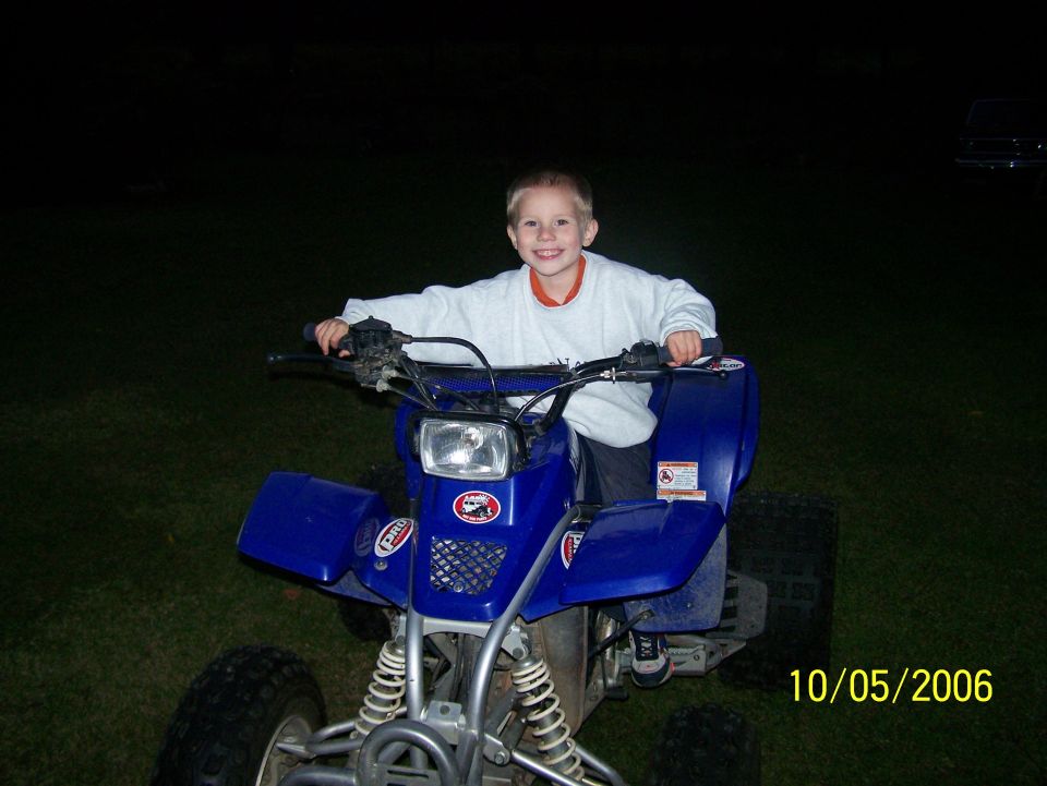 Young boy sitting on a blue Yamaha Blaster ATV at night, front view, dated 10/05/2006