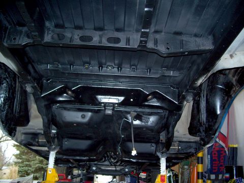 1971 Ford Ranchero - The undercarriage of a vehicle is visible, supported by yellow jack stands, with various mechanical parts exposed.