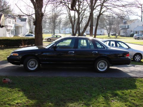 2003 Ford Crown Victoria - Side profile of a black 2003 Ford Crown Victoria sedan parked in a driveway.