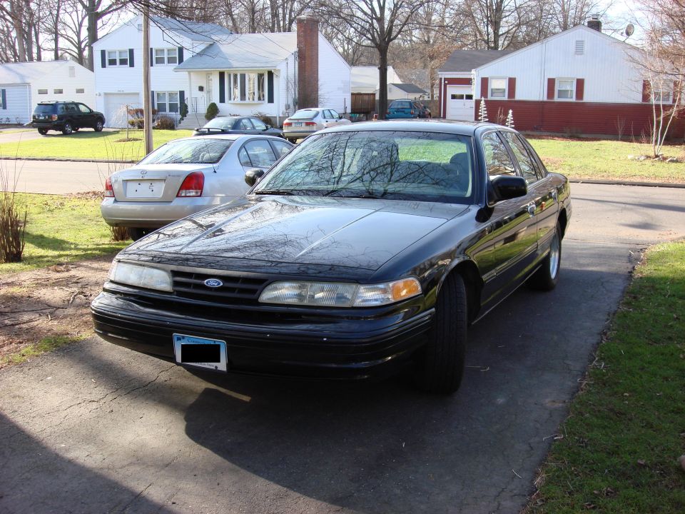 Black 2003 Ford Crown Victoria parked in driveway, silver sedan behind it