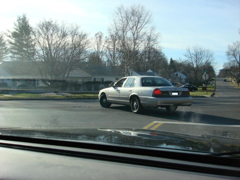 2003 Ford Crown Victoria sedan driving away from camera on a suburban street
