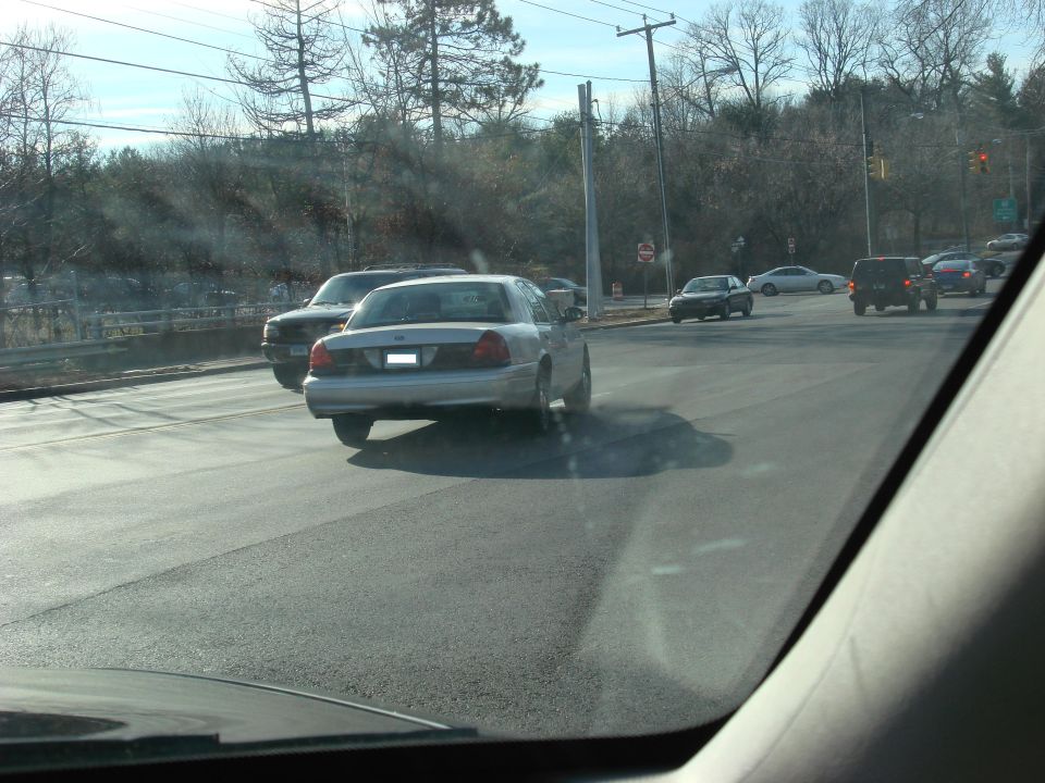 Silver 2003 Ford Crown Victoria driving on a road, seen from behind