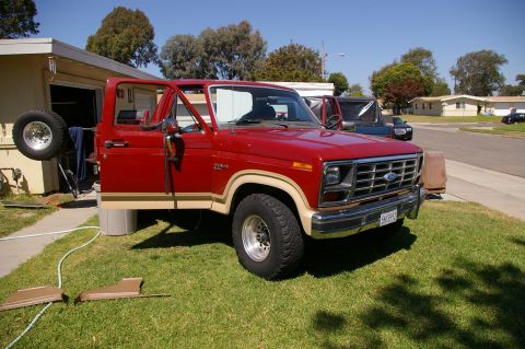 1986 Ford Bronco - This 1980s Ford pickup truck is parked in a residential driveway with its door open.